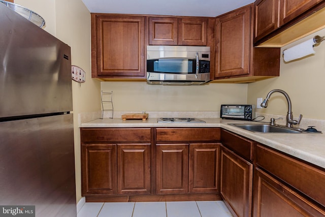 10900 Coastal Hwy Unit 209, Ocean City, MD 21842 - kitchen featuring stainless steel appliances, a sink, light countertops, and light tile patterned floors