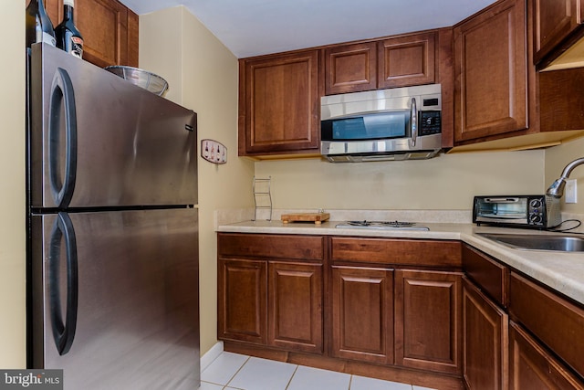 10900 Coastal Hwy Unit 209, Ocean City, MD 21842 - kitchen featuring appliances with stainless steel finishes, a sink, light countertops, and light tile patterned floors