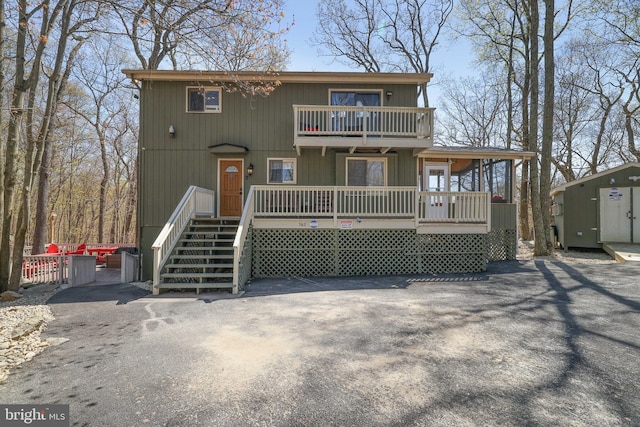 view of front of home featuring a balcony, stairs, an outdoor structure, and a shed