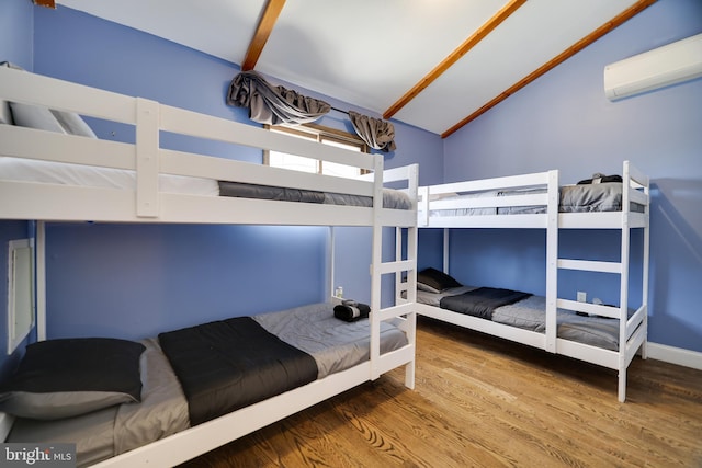 bedroom featuring a wall mounted AC, wood finished floors, lofted ceiling, and baseboards