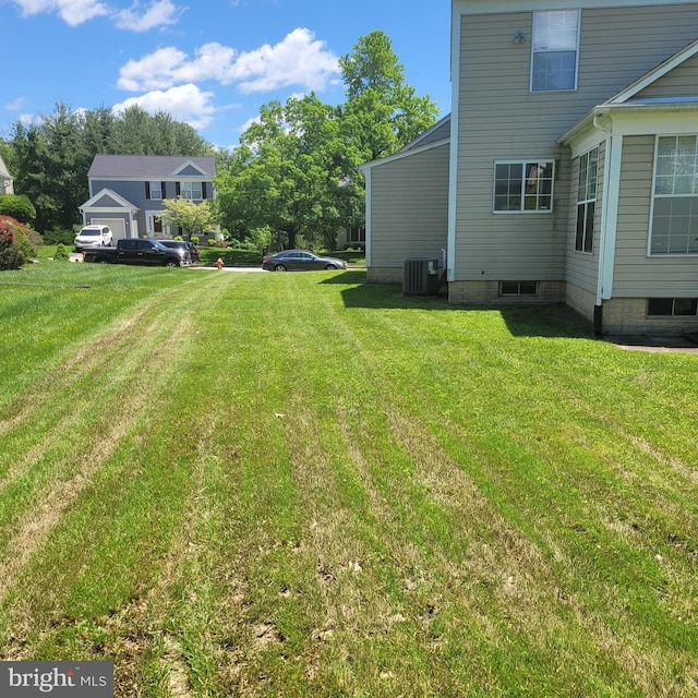 view of grassy yard featuring central AC unit