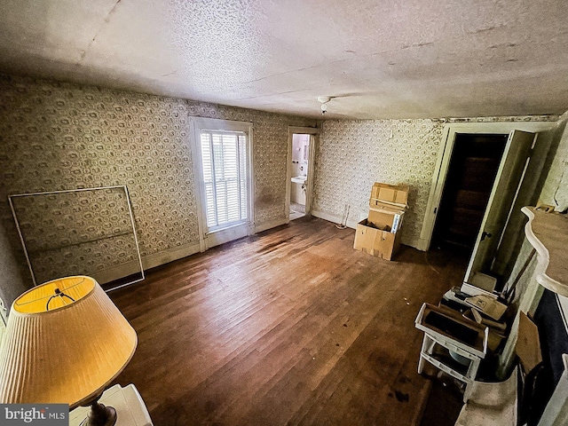 22446E Depot St, Newsoms, VA 23874 - unfurnished living room with wood-type flooring, a textured ceiling, baseboards, and wallpapered walls