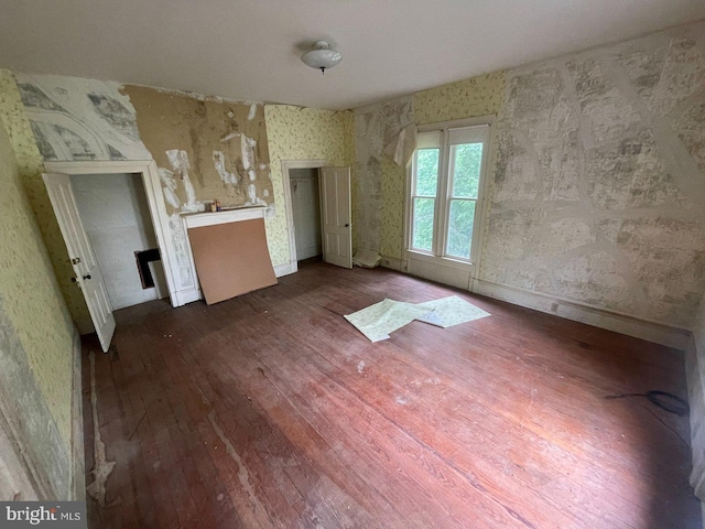 22446E Depot St, Newsoms, VA 23874 - unfurnished living room featuring wood-type flooring, wallpapered walls, and baseboards