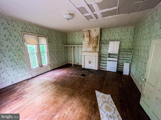 22446E Depot St, Newsoms, VA 23874 - unfurnished living room with wallpapered walls, dark wood-style floors, and baseboards