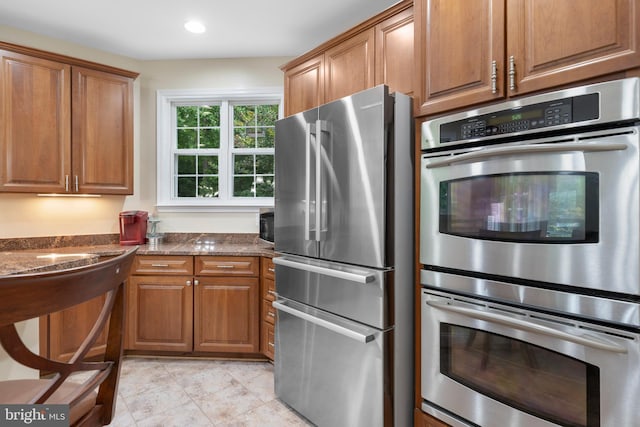 3740 Devin Ct, Huntingtown, MD 20639 - kitchen with appliances with stainless steel finishes, brown cabinets, dark stone countertops, light tile patterned floors, and recessed lighting