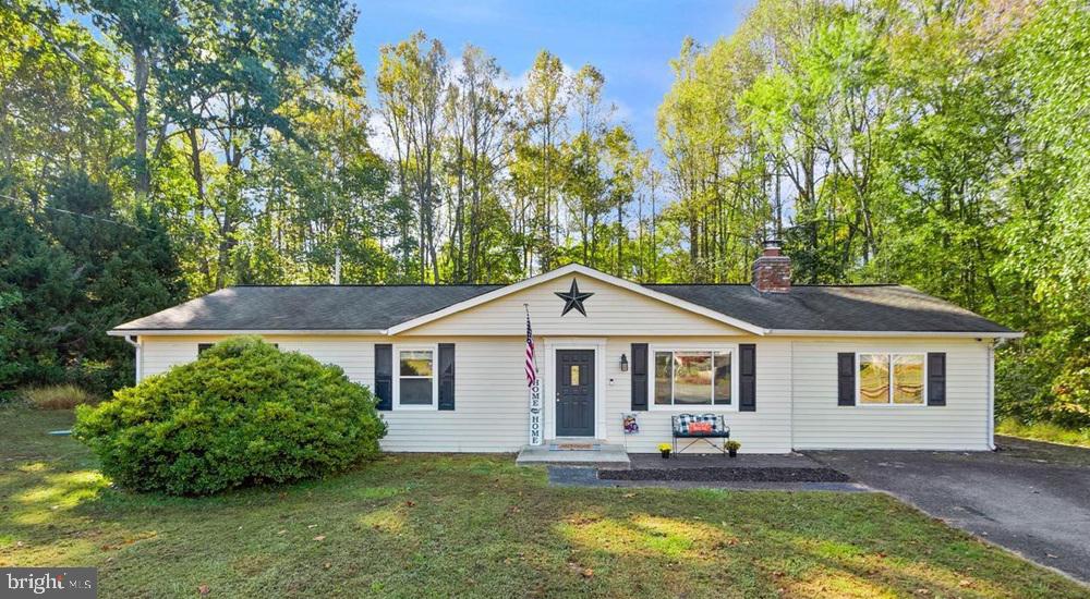 single story home featuring a chimney, a front yard, and driveway