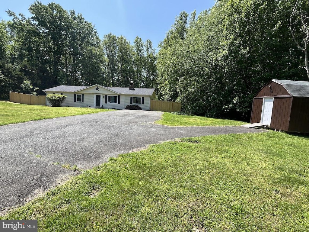 ranch-style house with a shed, an outbuilding, and asphalt driveway