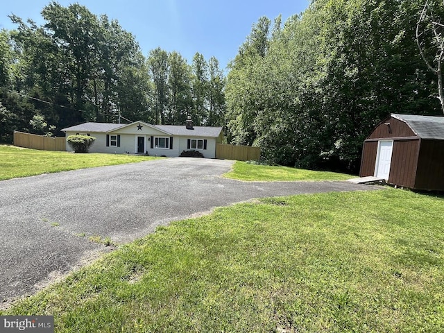 ranch-style house with a shed, an outbuilding, and asphalt driveway