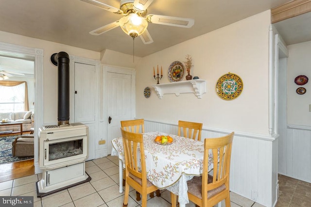 121 S Central St, Broadway, VA 22815 - dining room featuring ceiling fan, a wood stove, wainscoting, and light tile patterned floors