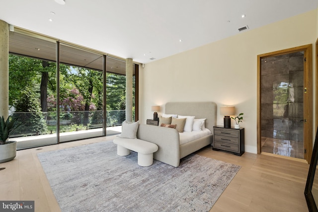 bedroom featuring a wall of windows, access to outside, multiple windows, and wood finished floors