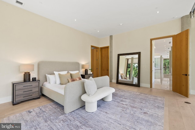 bedroom with light wood finished floors, ensuite bath, and recessed lighting