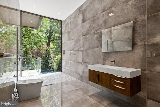 full bathroom featuring expansive windows, vanity, tile walls, healthy amount of natural light, and a soaking tub