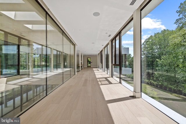 hallway featuring a wall of windows and wood finished floors