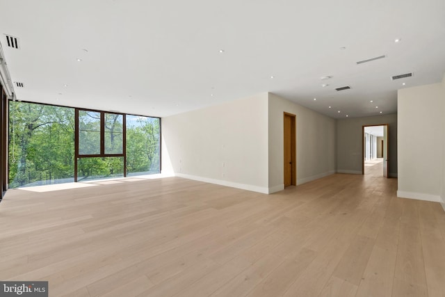 unfurnished room featuring light wood finished floors, baseboards, and expansive windows