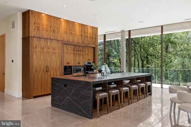 kitchen featuring expansive windows, plenty of natural light, brown cabinets, and a sink