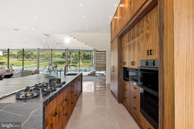 kitchen with modern cabinets, a sink, brown cabinets, and double wall oven