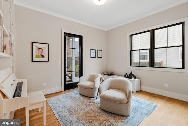 sitting room featuring crown molding, light wood-style floors, and baseboards