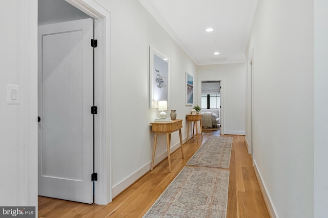 hallway featuring light wood-style flooring, crown molding, recessed lighting, and baseboards