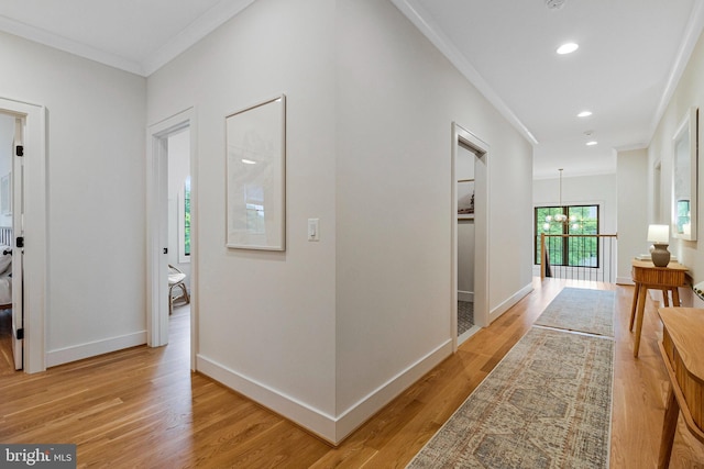 hall featuring crown molding, light wood-style flooring, baseboards, recessed lighting, and a chandelier