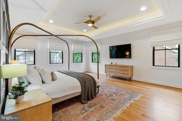 bedroom with a raised ceiling, wood finished floors, baseboards, recessed lighting, and a ceiling fan