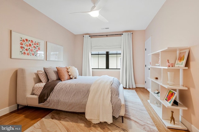bedroom featuring wood finished floors, baseboards, and a ceiling fan