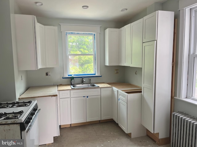 6709 N Lawrence St, Philadelphia, PA 19126 - kitchen featuring radiator, a sink, gas range gas stove, and white cabinetry
