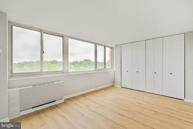 4520 King St Unit 609, Alexandria, VA 22302 - unfurnished bedroom with radiator heating unit, light wood-style floors, and baseboards