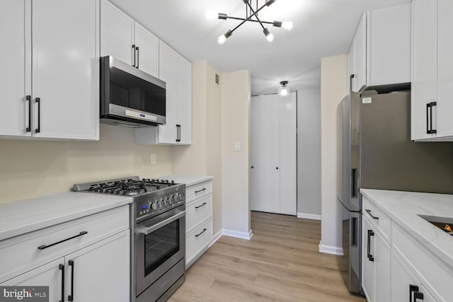 4520 King St Unit 609, Alexandria, VA 22302 - kitchen with appliances with stainless steel finishes, a chandelier, white cabinets, light wood finished floors, and baseboards