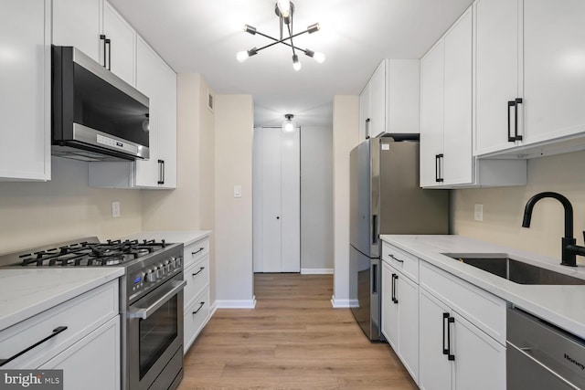 4520 King St Unit 609, Alexandria, VA 22302 - kitchen with appliances with stainless steel finishes, a sink, a chandelier, light wood-style flooring, and white cabinets