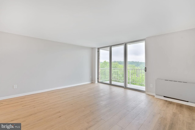 4520 King St Unit 609, Alexandria, VA 22302 - spare room featuring expansive windows, baseboards, light wood finished floors, and radiator heating unit