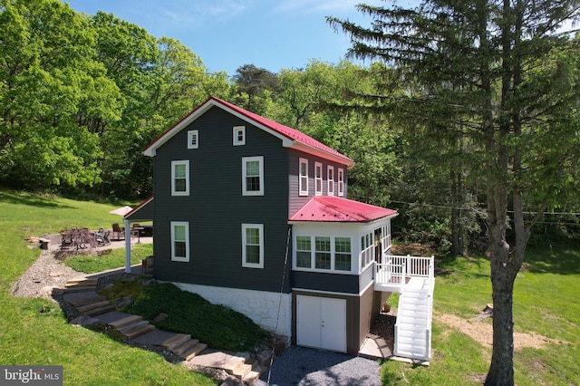 view of home's exterior with stairs, a lawn, metal roof, and a deck