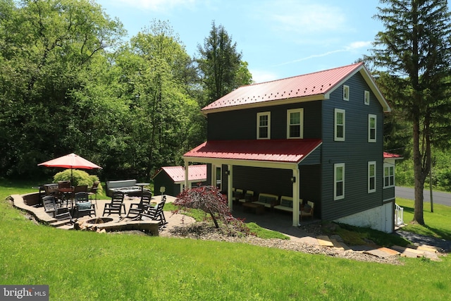 rear view of house featuring a yard, metal roof, and a patio