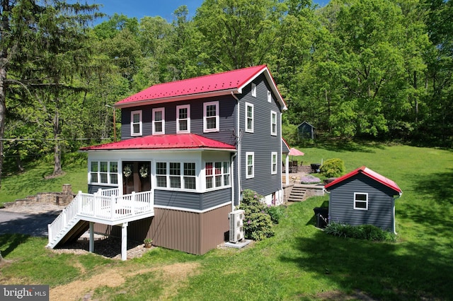 back of property with stairway, a wooden deck, metal roof, a lawn, and a wooded view