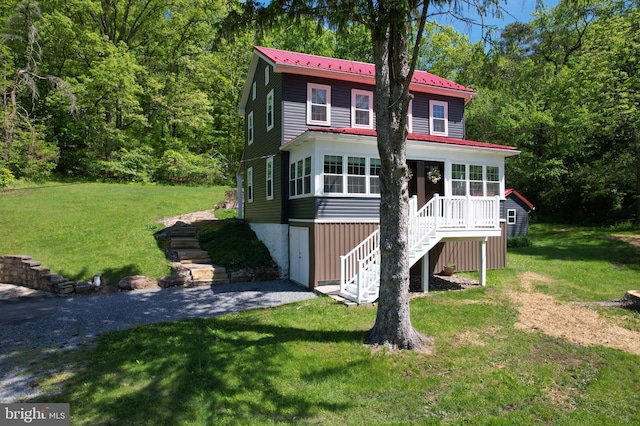 view of front of home featuring stairway, a front lawn, metal roof, a wooden deck, and a forest view