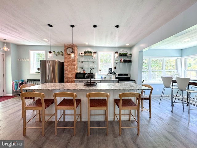 kitchen featuring appliances with stainless steel finishes, open shelves, a center island, and light wood-style flooring
