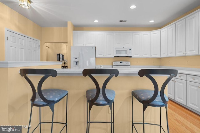 52 Whitewater Dr, Barnegat, NJ 08005 - kitchen featuring white appliances, a kitchen bar, white cabinetry, light wood-style flooring, and light countertops