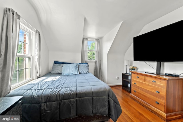 bedroom featuring wood finished floors, vaulted ceiling, and baseboards