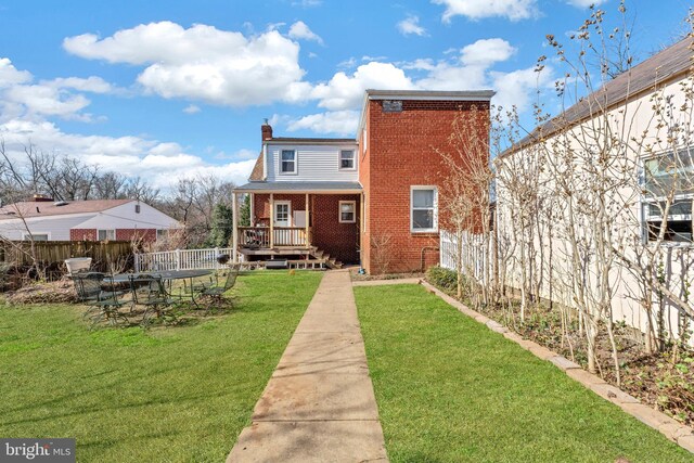 rear view of property with brick siding, a chimney, and a deck