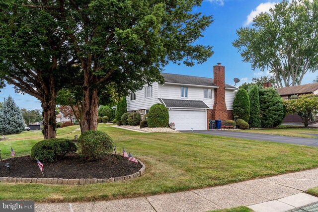 traditional-style home with driveway, a garage, a front yard, and a chimney
