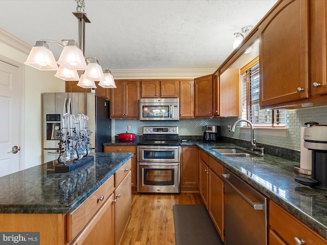 2079 Stoneleigh Dr, Winchester, VA 22601 - kitchen with stainless steel appliances, a sink, brown cabinets, light wood-type flooring, and a textured ceiling