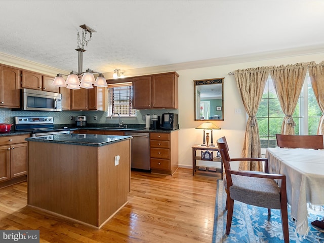 2079 Stoneleigh Dr, Winchester, VA 22601 - kitchen featuring stainless steel appliances, a sink, dark countertops, light wood-type flooring, and crown molding