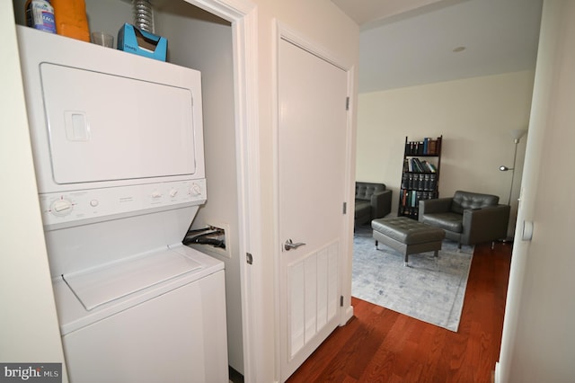 clothes washing area featuring stacked washer and clothes dryer and dark wood-type flooring