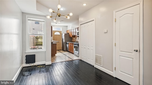1321 W St SE, Washington, DC 20020 - kitchen with appliances with stainless steel finishes, baseboards, a chandelier, wood finished floors, and brown cabinetry
