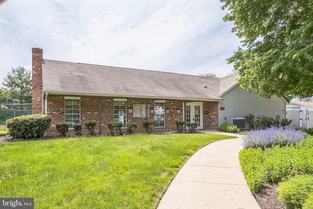 view of front facade featuring brick siding, a chimney, a shingled roof, and french doors
