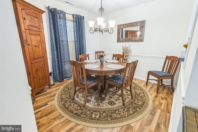 dining space featuring a chandelier, light wood-style flooring, and baseboards