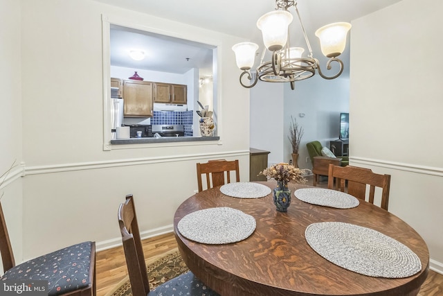 dining area with wood finished floors, a chandelier, and baseboards