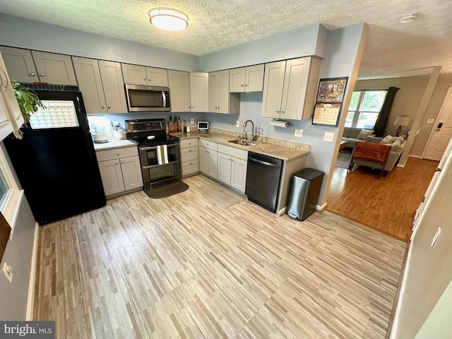 18628 Winding Creek Pl, Germantown, MD 20874 - kitchen with black appliances, a sink, light wood-style flooring, a textured ceiling, and gray cabinetry