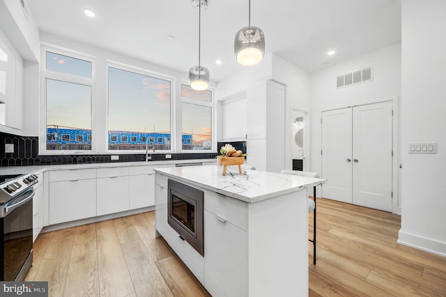 2201 E Somerset St Unit B3Lower, Philadelphia, PA 19134 - kitchen featuring appliances with stainless steel finishes, modern cabinets, a kitchen bar, white cabinetry, and light wood finished floors