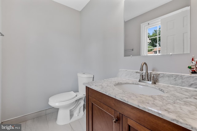 bathroom with toilet, vanity, and baseboards