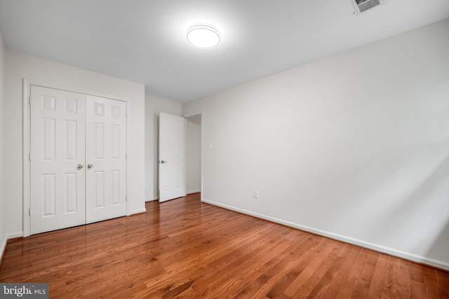 unfurnished bedroom with wood finished floors, a closet, and baseboards